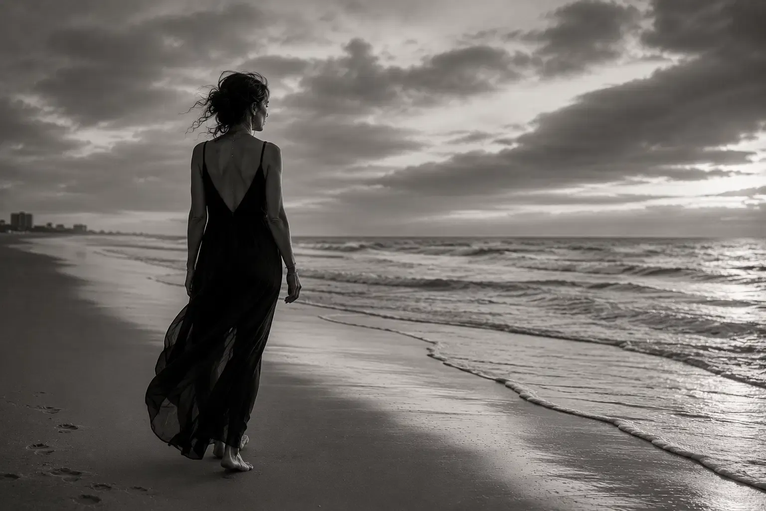 A woman walking at the edge of the sea, looking toward the horizon